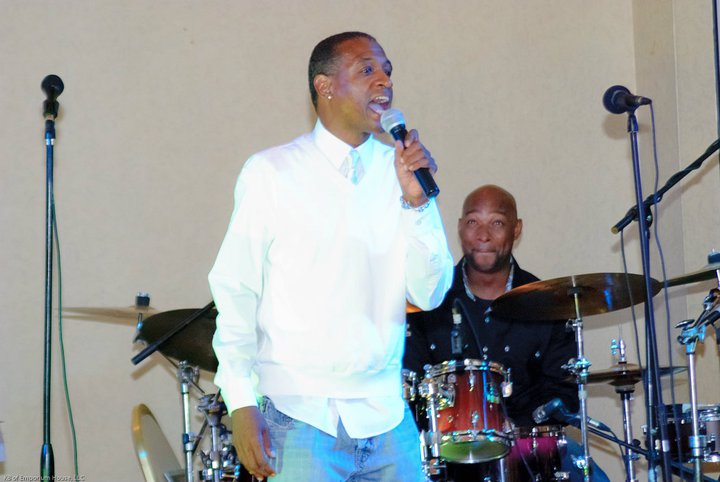Singer performing live with a drummer on stage
