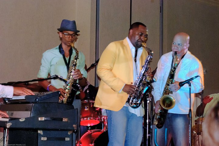Three saxophonists performing together on stage